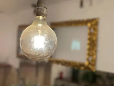 a glass light bulb hanging from a wall with a mirror at CasaHotel Jockey Plaza Mall in Lima