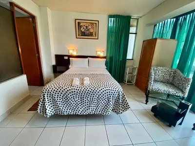 a bedroom with a bed and a chair at CasaHotel Jockey Plaza Mall in Lima