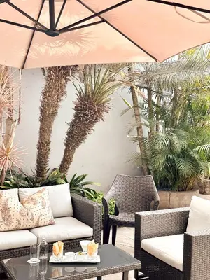 a patio with chairs and an umbrella and palm trees at El Golf Hotel Boutique in Lima