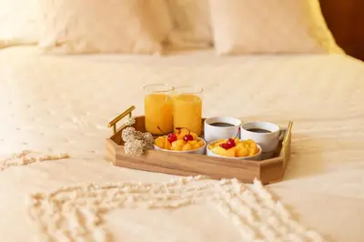 a tray of fruit and two glasses of juice on a bed at Hotel Park Suites in Lima