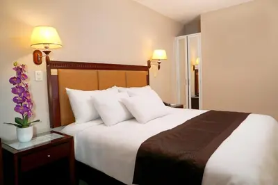 a hotel room with a large bed with white pillows at Gran Mundo Hotel & Suites in Lima