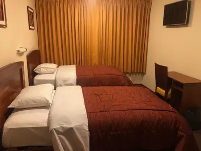 a hotel room with two beds and a window at Illariy Hotel in Huancavelica