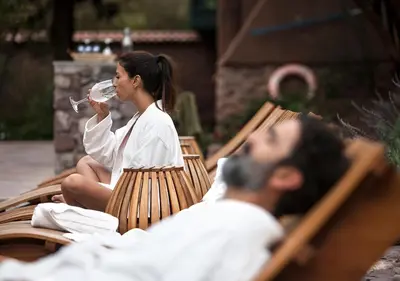 a man and woman sitting on a bench drinking wine at Explora Valle Sagrado in Urubamba