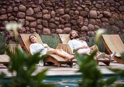 a man and woman sitting in chairs by a pool at Explora Valle Sagrado in Urubamba