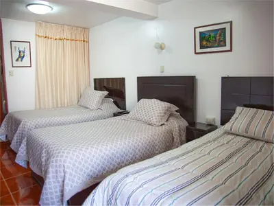 two beds in a room with white walls at Casa de Laura in Cusco