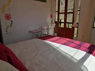 a bedroom with a bed and a desk and a window at Hostal Chaska Wasi in Ollantaytambo