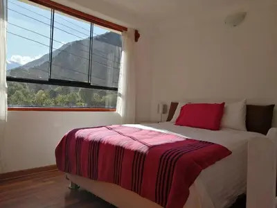 a bedroom with a bed and a large window at Hostal Chaska Wasi in Ollantaytambo