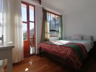 a bedroom with a bed and a large window at Hostal Chaska Wasi in Ollantaytambo
