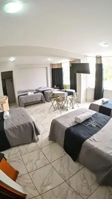 a room with four beds and a table in it at Regency Plaza Hotel in Pisco