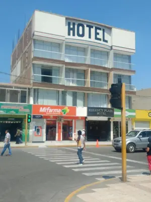 a hotel building on a city street with people crossing the street at Regency Plaza Hotel in Pisco