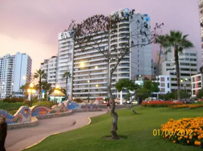 a park in a city with a large building at Miraflores Departamentos in Lima