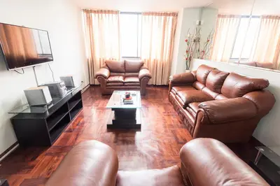 a living room with leather couches and a coffee table at Apartment Miraflores Pardo in Lima