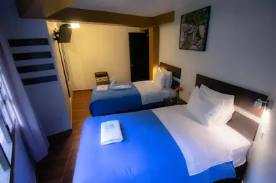 a hotel room with two beds and a mirror at Samananchis Machupicchu in Machu Picchu