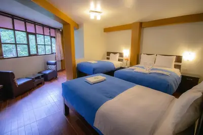 a hotel room with two beds and a chair at Samananchis Machupicchu in Machu Picchu