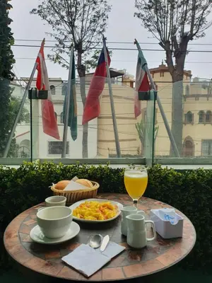 a table with a plate of food and a glass of orange juice at Residencial Alfa Hotel in Lima