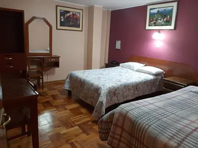 a hotel room with two beds and a mirror at Hotel Las Lomas in Huancayo