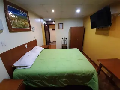 a bedroom with a green bed and a flat screen tv at Hotel Las Lomas in Huancayo