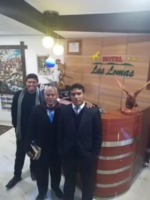 three men in suits standing in front of a bar at Hotel Las Lomas in Huancayo