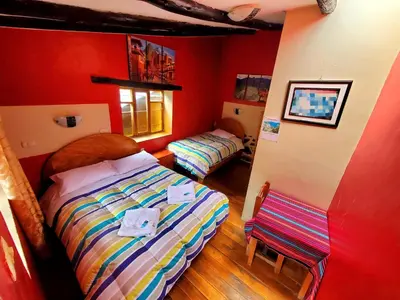 two beds in a room with red walls at Hospedaje K'uchuwasi in Ollantaytambo