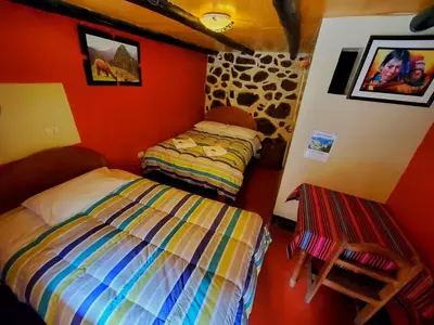 two beds in a room with red walls at Hospedaje K'uchuwasi in Ollantaytambo