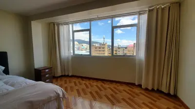 a bedroom with a large window with a view of a city at Hotel Wanka Palace in Huancayo