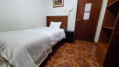 a bedroom with a white bed and a wooden floor at Hotel Wanka Palace in Huancayo