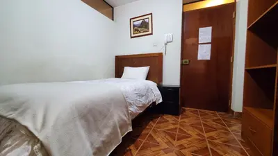 a bedroom with a white bed and a wooden door at Hotel Wanka Palace in Huancayo