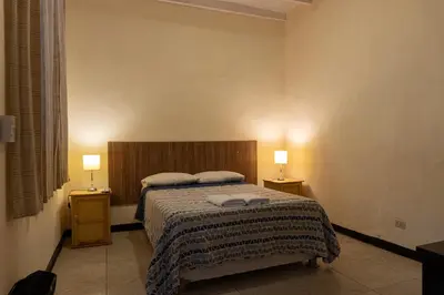 a bedroom with a bed and two lamps on two tables at Wild Olive Guest House in Ica