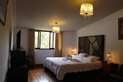 a bedroom with a bed with white sheets and a window at Hotel de Turistas Abancay in Abancay