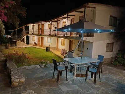 a table with chairs and an umbrella in front of a house at Casa de Mama Valle - Urubamba in Urubamba
