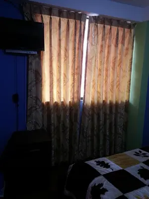 a bedroom with a bed and a window with a curtain at Hostal Arcangel in Abancay