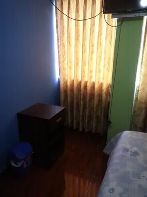 a bedroom with a bed and a dresser and a curtain at Hostal Arcangel in Abancay