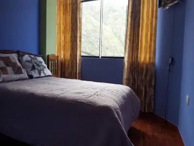 a blue bedroom with a bed and a window at Hostal Arcangel in Abancay