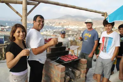 a group of people standing around a grill at Cruz del Sur in Pucusana