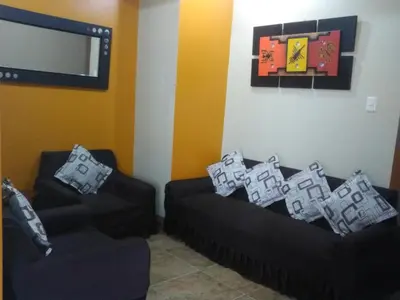 a living room with two black couches and a tv at Starlight Inn in Pisco