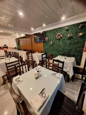 a restaurant with white tables and chairs and flowers on the wall at Andino Classic in Machu Picchu