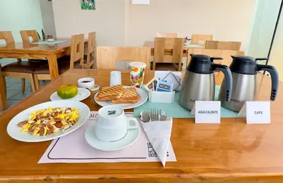 a wooden table with plates of food and a coffee maker at Hotel Asturias Inn in Lima