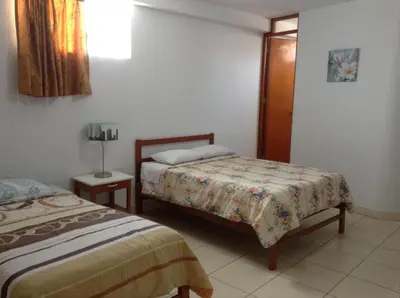 a bedroom with two beds and a lamp in it at Hostal La Estancia in Ica