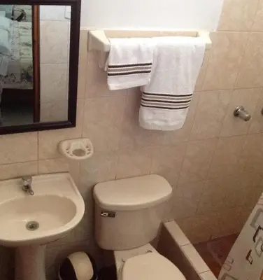 a bathroom with a toilet and a sink and towels at Hostal La Estancia in Ica