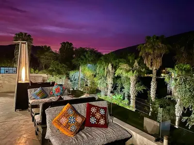 a patio with a couch and palm trees at night at Desert Nights Hostel in Ica