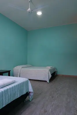 two beds in a room with blue walls and wooden floors at Desert Nights Hostel in Ica