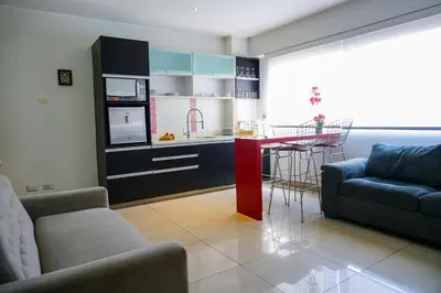 a living room with a couch and a table and a kitchen at Apart Hotel Petit Palace Suites in Lima