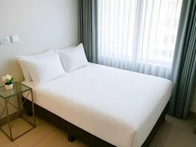a white bed in a room with a window at Apart Hotel Petit Palace Suites in Lima