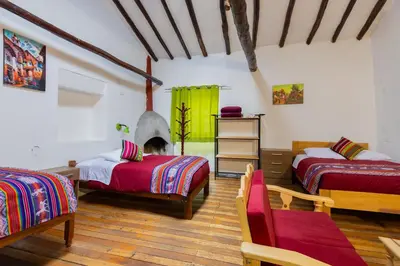 a room with two beds and two chairs in it at Tucan Hostel in Cusco