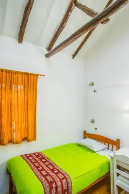 a bedroom with a green bed and a window at Tucan Hostel in Cusco