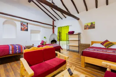 a bedroom with two beds and a couch and a fireplace at Tucan Hostel in Cusco