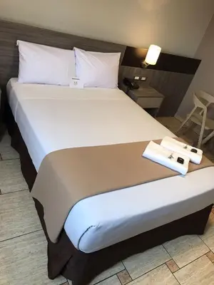 a bed in a hotel room with two towels on it at Hotel Mega in Lima