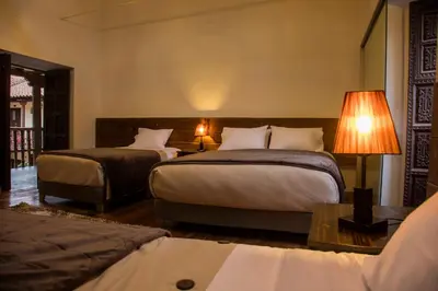 a hotel room with two beds and a lamp at Hotel Casa Fierro Cusco in Cusco