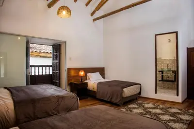 a hotel room with two beds and a mirror at Hotel Casa Fierro Cusco in Cusco