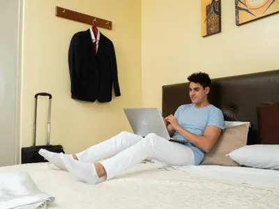 a man sitting on a bed with a laptop at Hotel Queen in Lima
